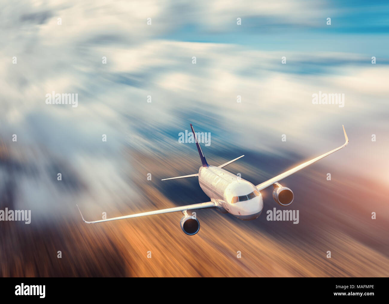 Modern airplane with motion blur effect is flying over low clouds at ...