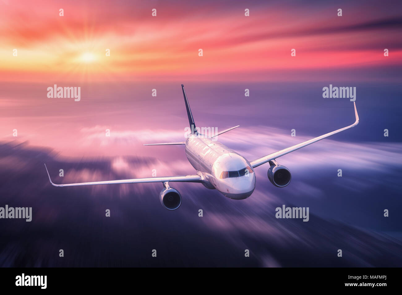 Modern airplane with motion blur effect is flying over low clouds at ...
