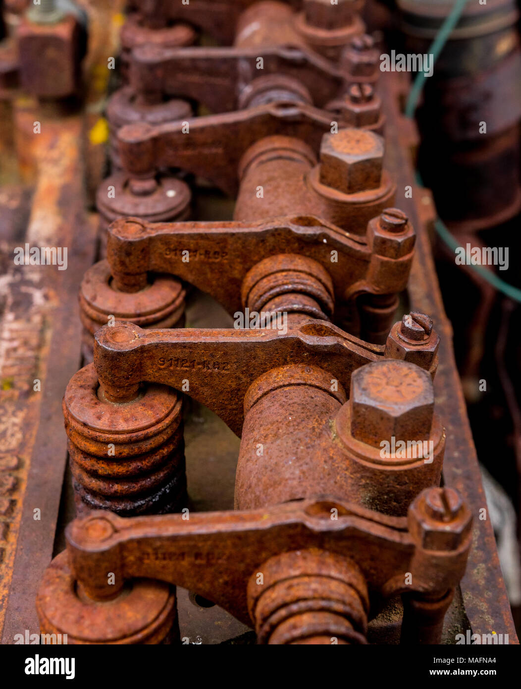 Vintage antique automotive cylinder head rocker shaft, arms, and springs covered in rust and oxidation. Stock Photo