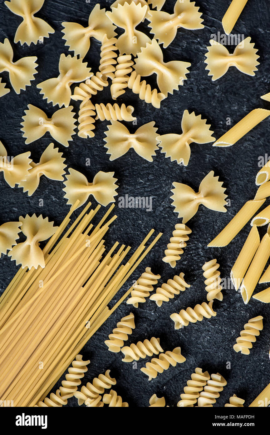 Assorted uncooked raw pasta on black background. Italian pasta penne