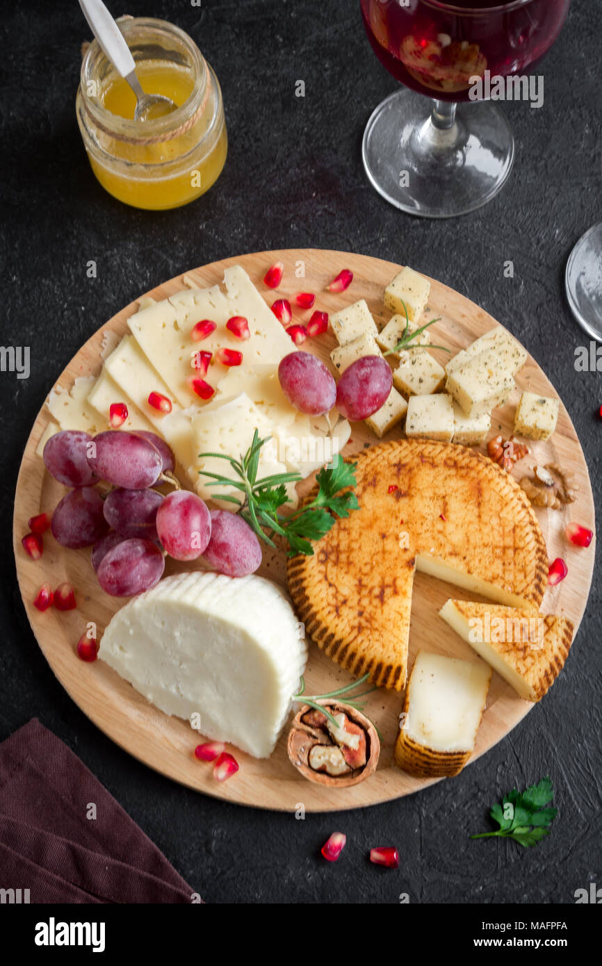 Cheese platter with assorted cheeses, grapes, nuts over black