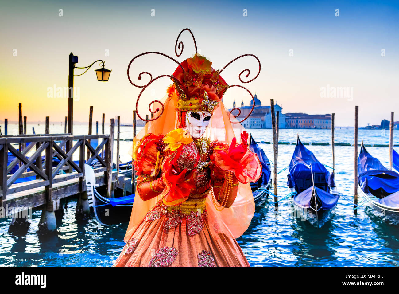Venice, Italy - 9th February 2018: Carnival of Venice, beautiful mask at Piazza San Marco with gondolas and Grand Canal. Stock Photo