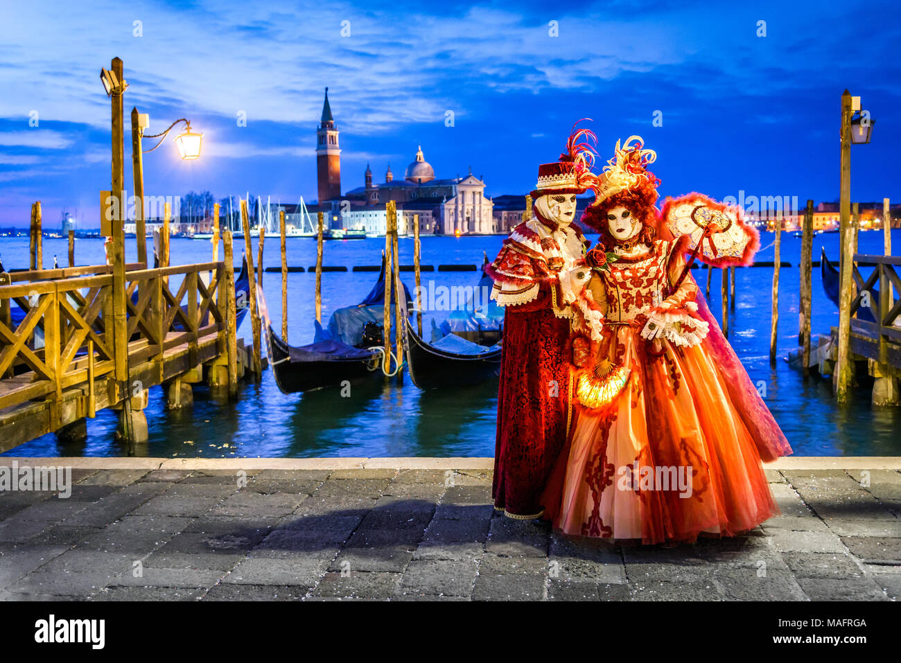 Venice, Italy - 11th February 2018: Carnival of Venice, beautiful mask at Mark's Square with St. George island in the background. Stock Photo