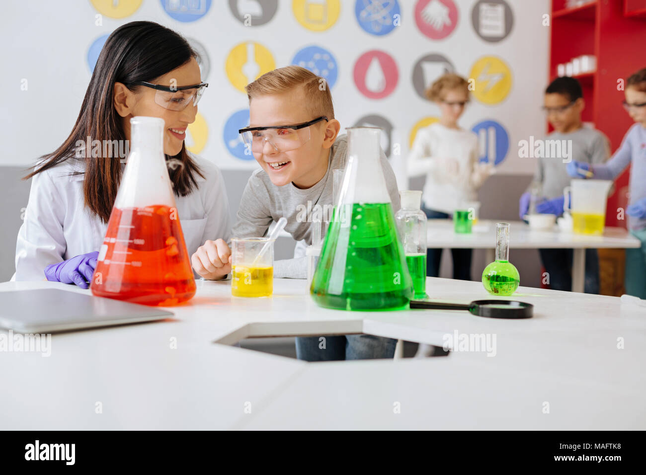 Joyful chemistry teacher and student talking about experiment and laughing Stock Photo