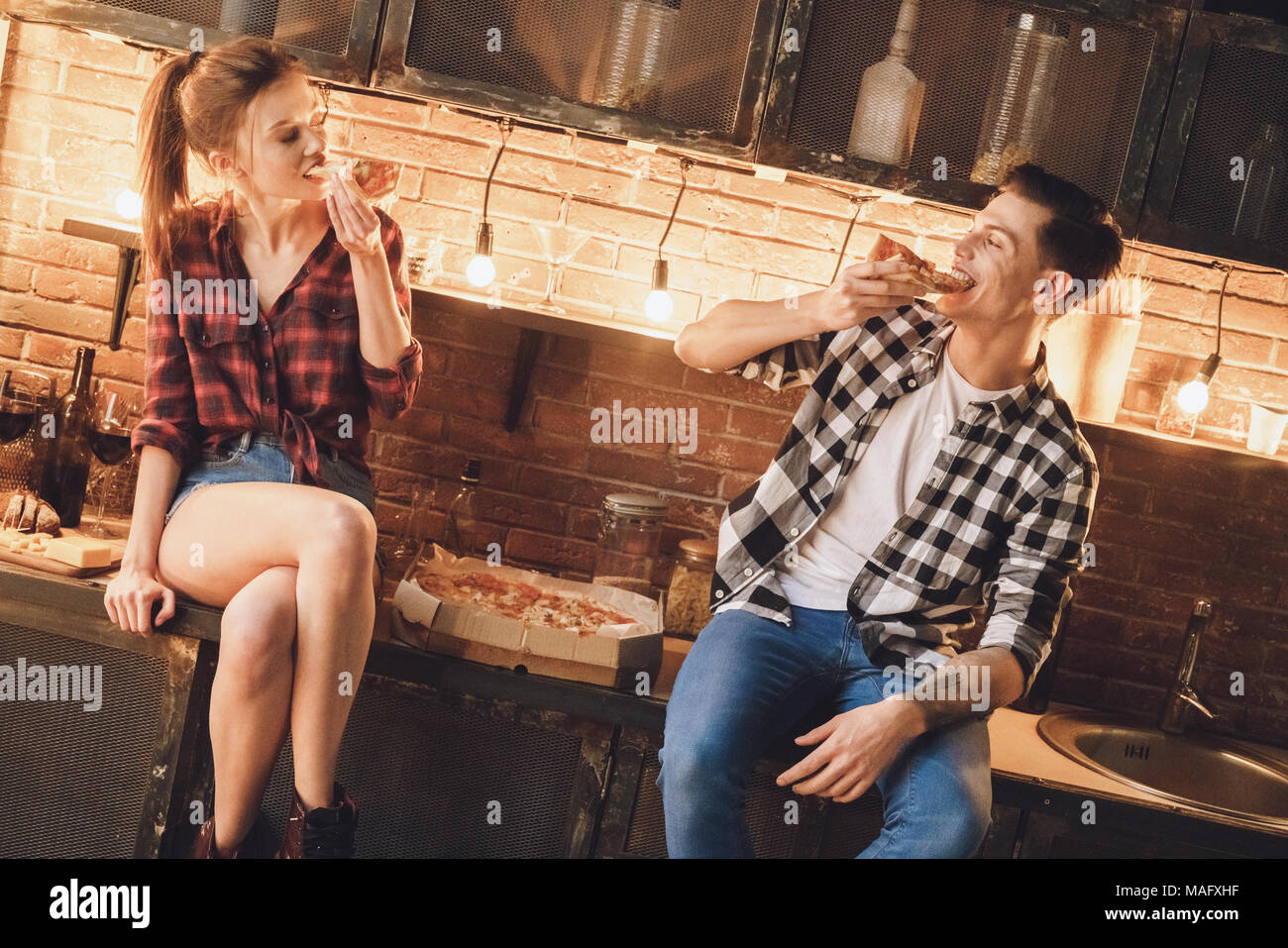 Couple don't cooking. Enjoy and eating buy pizza. Indoor, kitchen home interior, studio shot. Stock Photo