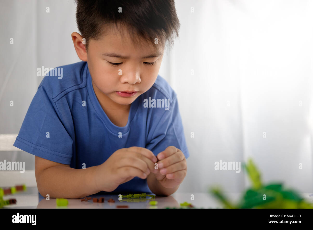 Cute asian boy is playing with blocks from toy constructor with copy space. Educational toys concept. Stock Photo