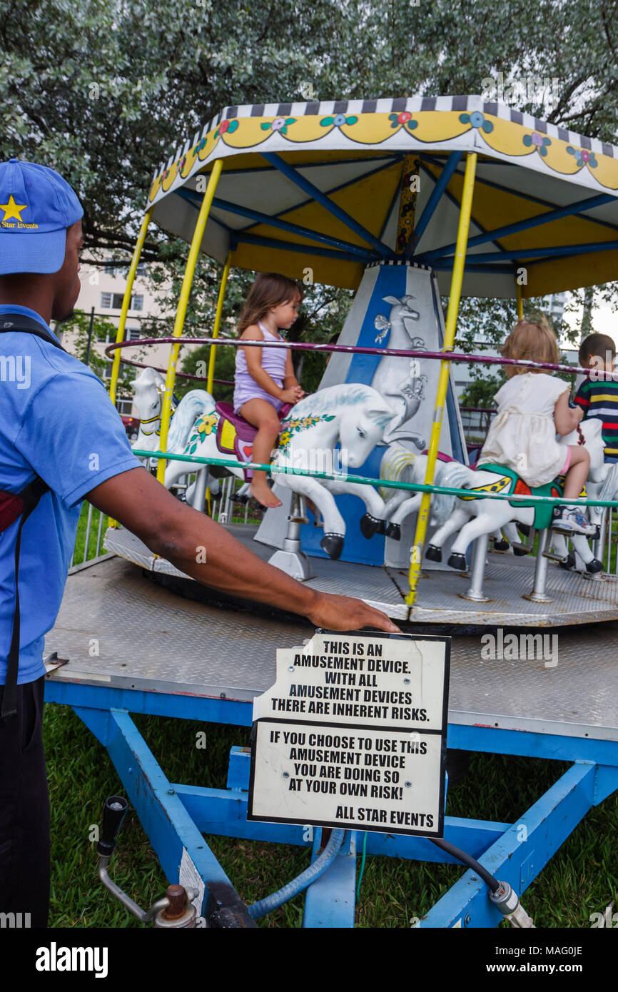 Miami Beach Florida,Flamingo Park,School's Out Fiesta community merry go round,amusement ride,sign,at your own risk,disclaimer,Black man men male,ride Stock Photo