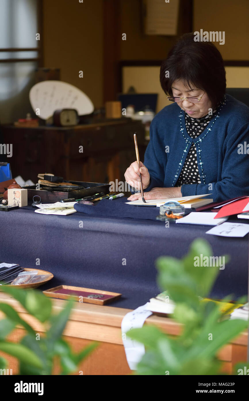 Japanese woman calligrapher writing at a desk Uji, Japan Stock Photo