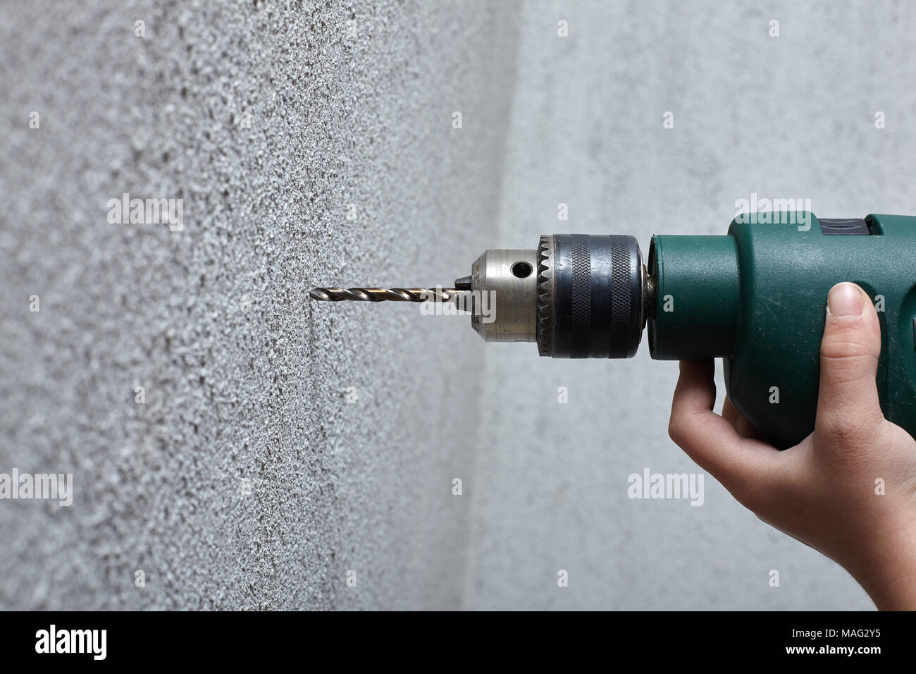 Worker drilling a hole into the wall with an electric drill Stock Photo