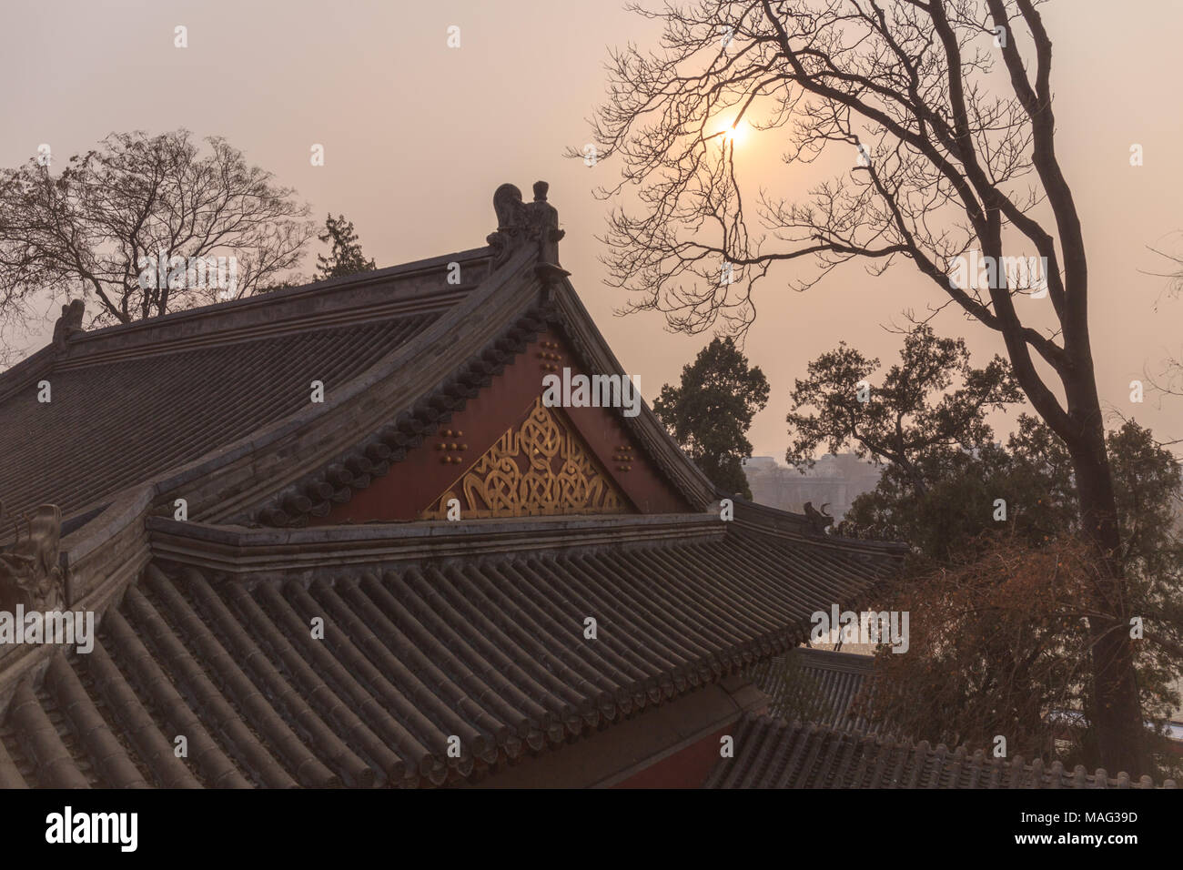 Smoggy sunset over historic temples at Beihai Park in Beijing, China. Stock Photo