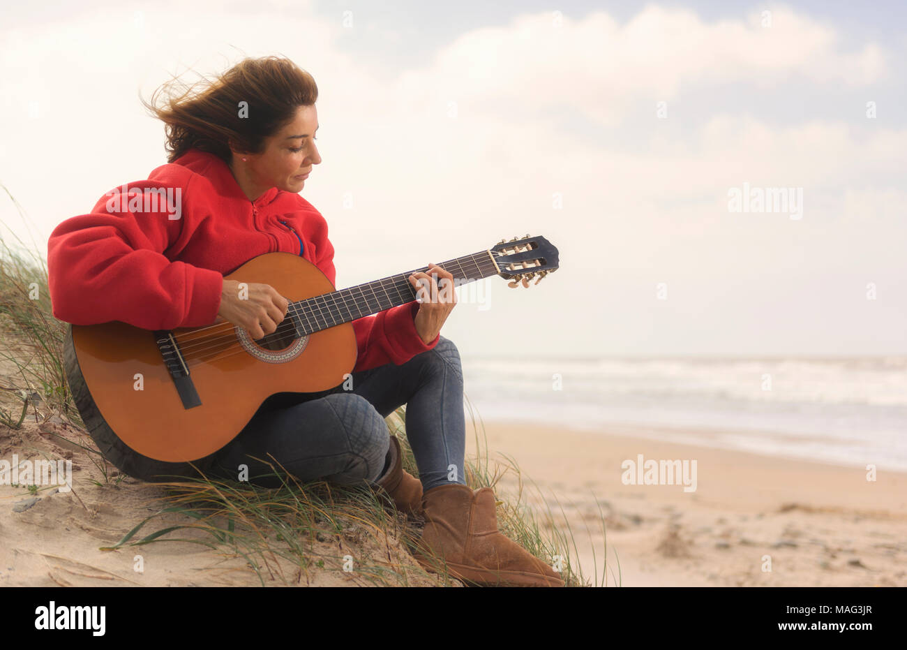 Woman playing her guitar at the beach. Tarifa, Costa de la Luz, Cadiz, Andalusia, Spain. Stock Photo