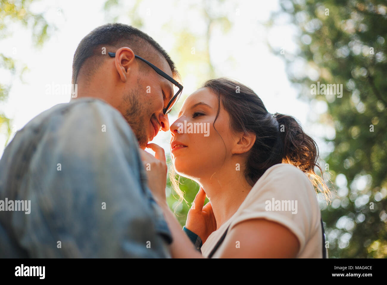Beautiful young couple kiss and hug in a summer park near trees Stock Photo