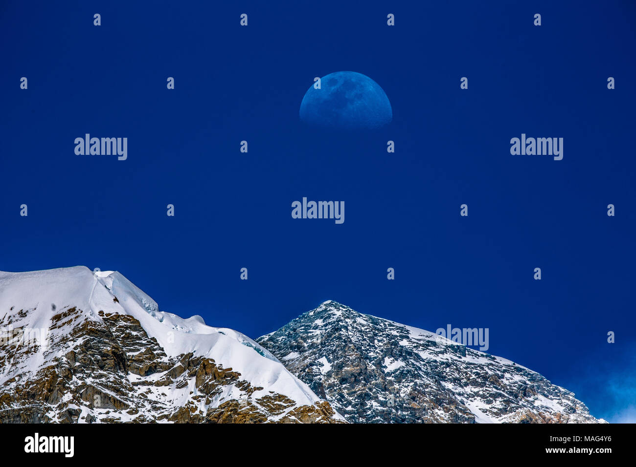 A half moon rises right over the peak of Mount Everest, during climbing season, Nepal Stock Photo