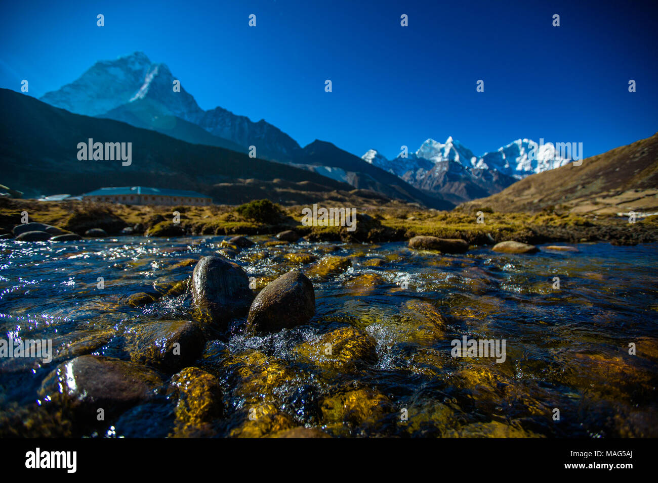 A tranquil stream of water passes down the valley towards Ama Dablam in the Himalayas, Pheriche, Nepal Stock Photo