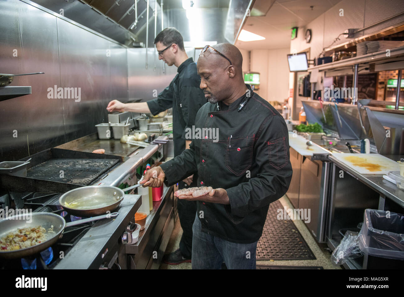 Chef David Thomas pan-searing a catfish fillet in butter in the kitchen at Ida B's Table Stock Photo