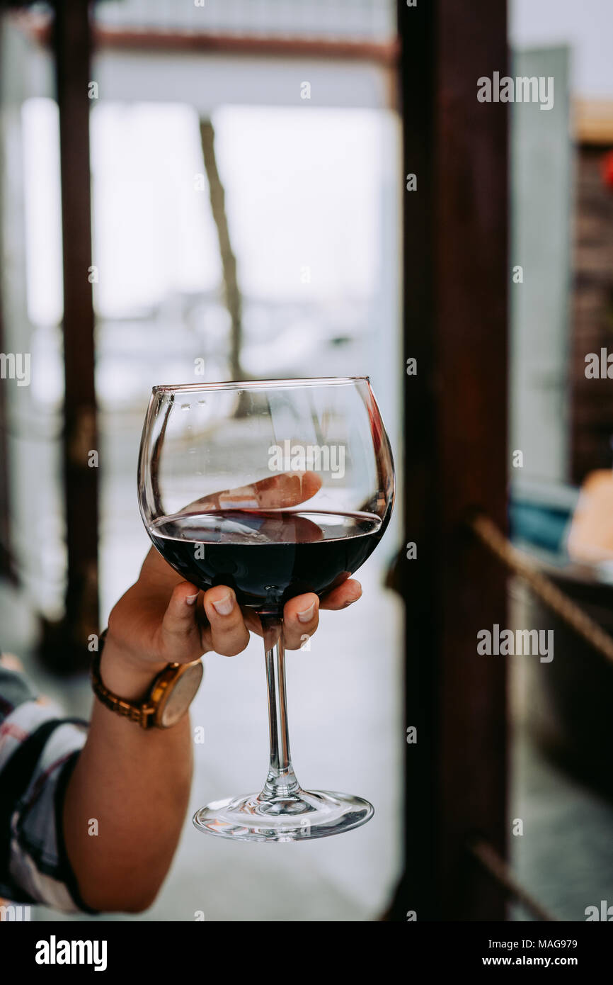 Woman hand holding a wine glass with red wine Stock Photo - Alamy