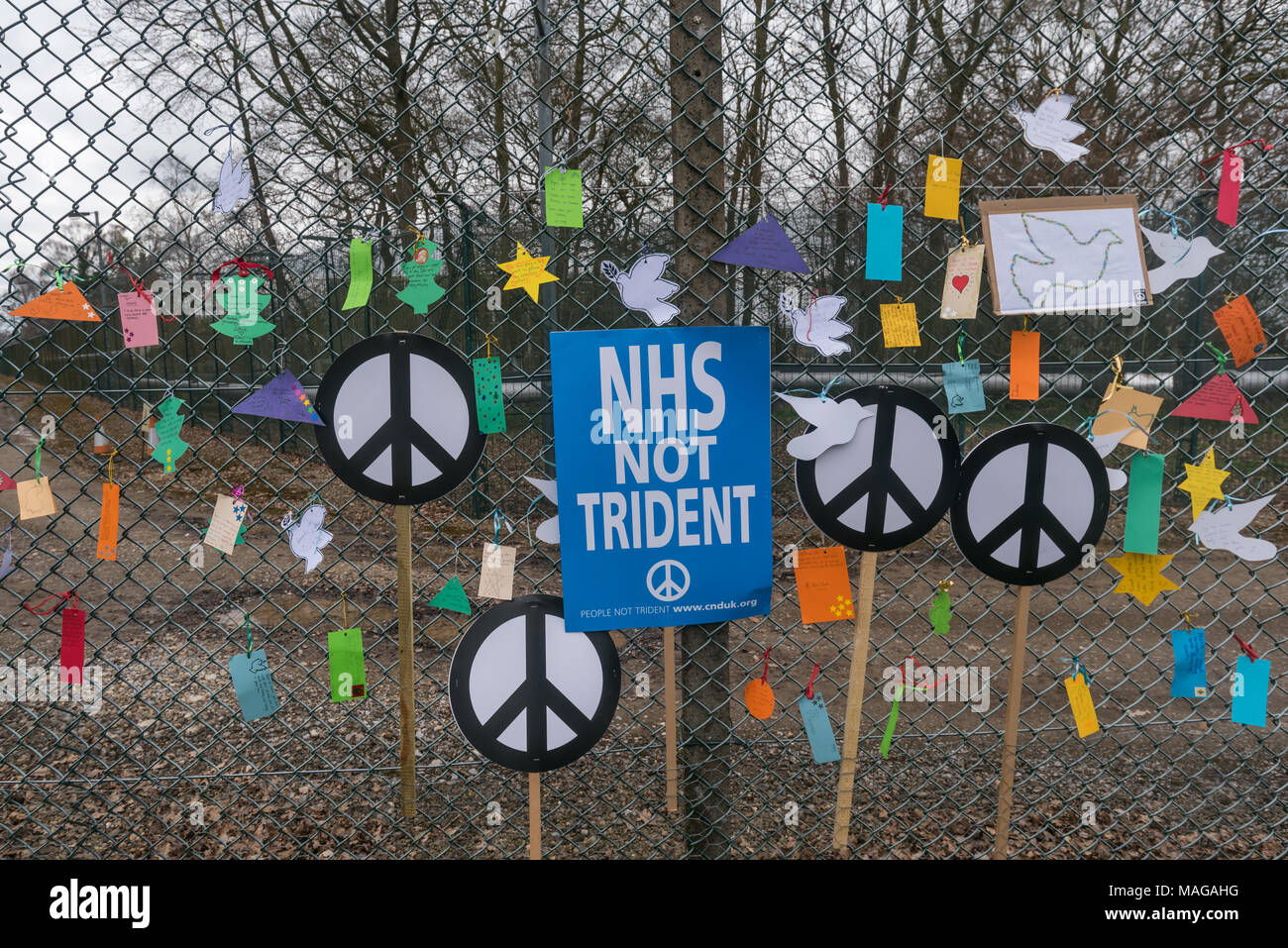 Aldermaston, UK. 1st Apr, 2018. Placards with doves and peace messages tied on the security fence of AWR Aldermaston as CND celebrates the 60th anniversary of the first Aldermaston march which mobilised thousands against the Bomb and shaped radical protest for generations. Their protest outside the Atomic Weapons Establishment included a giant, iconic peace symbol, speeches, including by some of those on the original march, singing and drumming and celebrated the UN treaty banning nuclear weapons. Credit: Peter Marshall/Alamy Live News Stock Photo