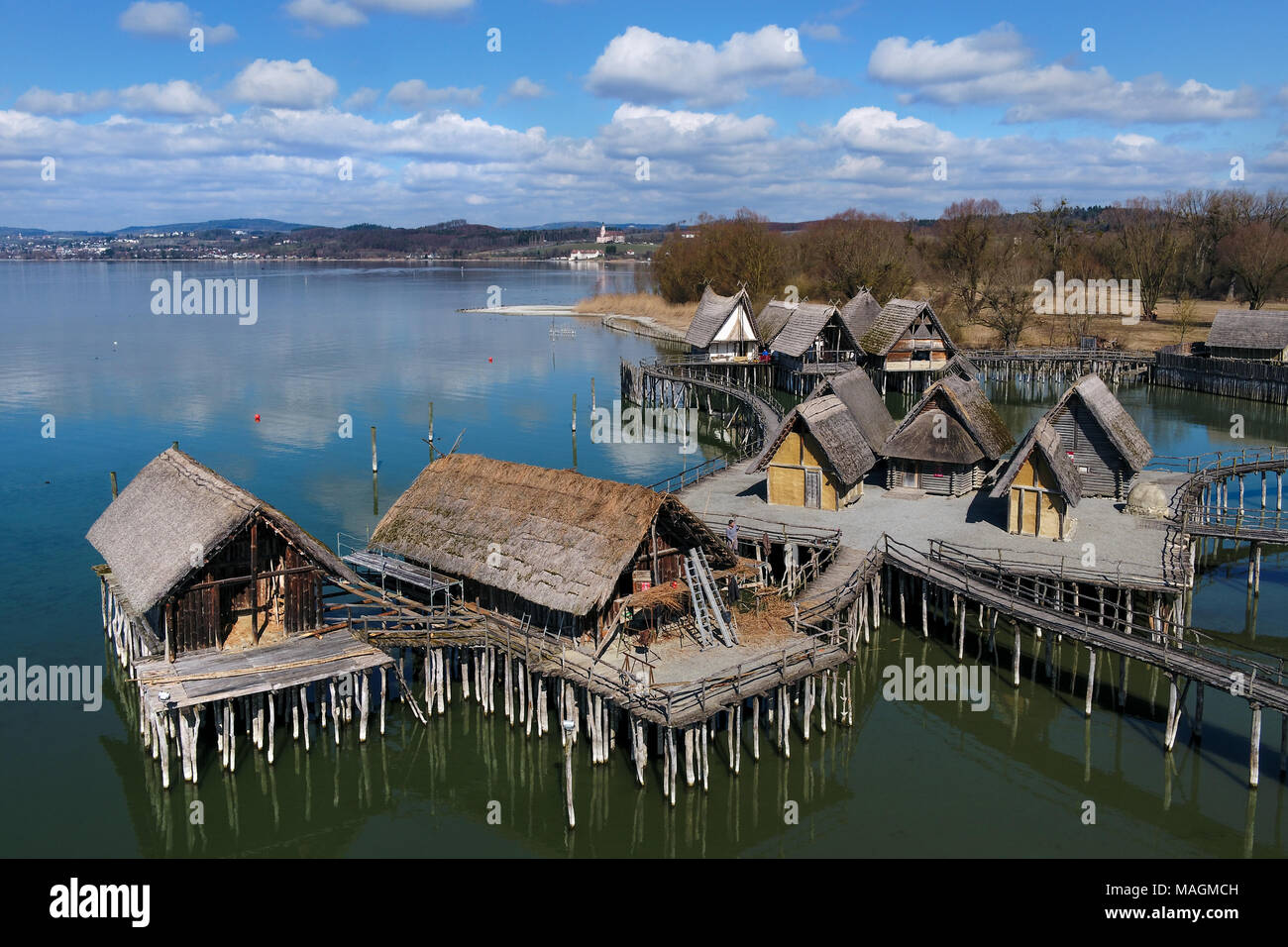 14 March 2018, Germany, Unteruhldingen-Muehlhofen: Craftsmen repair the roof of the oldest lake dwelling house (2-L), which is 96 years old, at the pile-dwelling museum at Lake Constance. (taken with drone) Photo: Felix Kästle/dpa Stock Photo