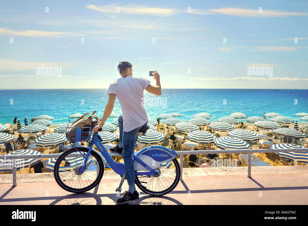 Street scene with bicycler and sunshades on luxury beach. Nice, France, Cote d'Azur Stock Photo