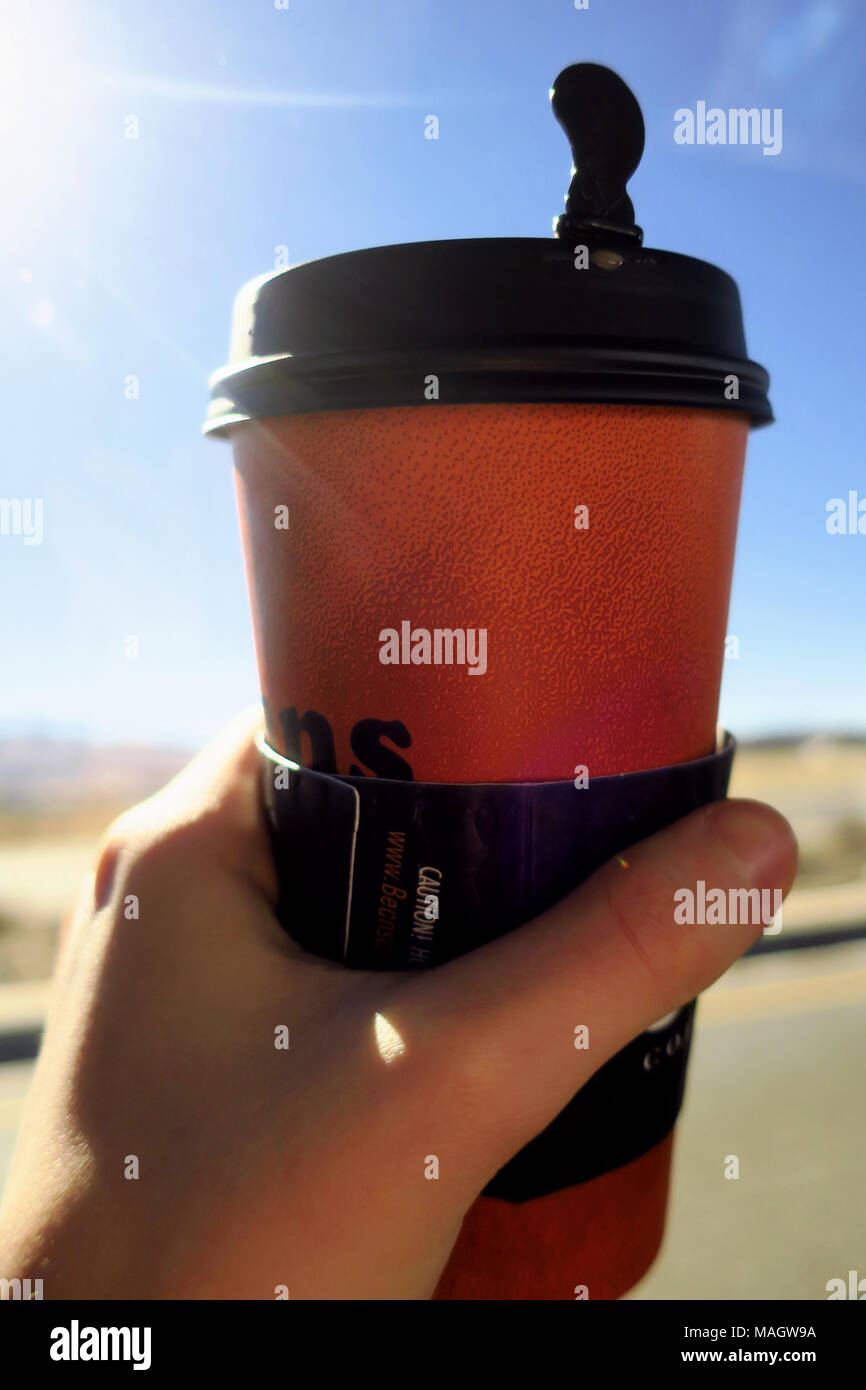 A man holding up a coffee cup to the sun. Stock Photo