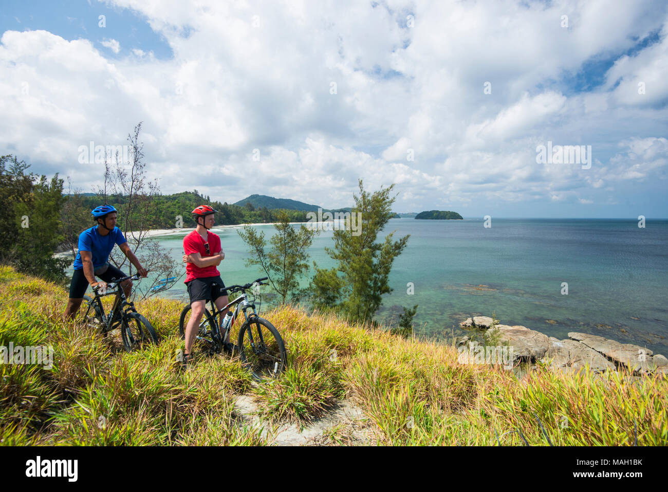 Guys cycling along a headland, Kudat, Sabah, Malaysia, Borneo, Stock Photo