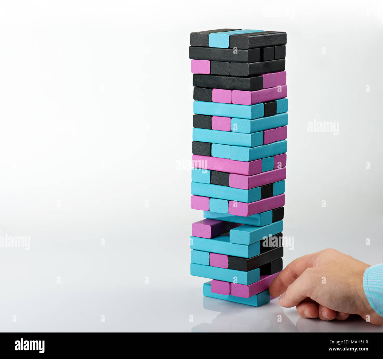Take one brick from wooden tower. Balancing tower concept Stock Photo