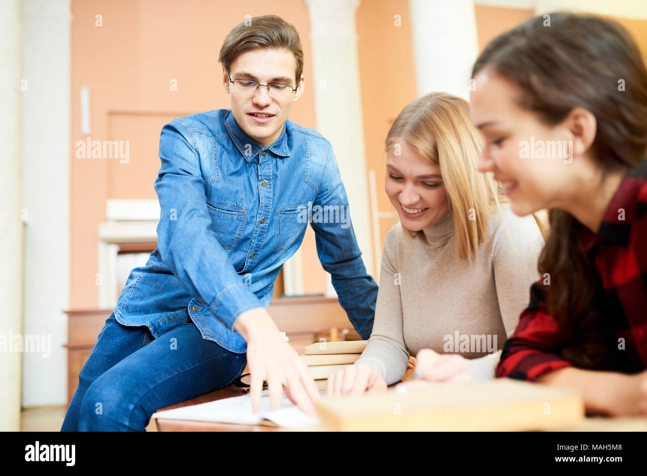 Ecstatic students discussing textbook contain in library Stock Photo