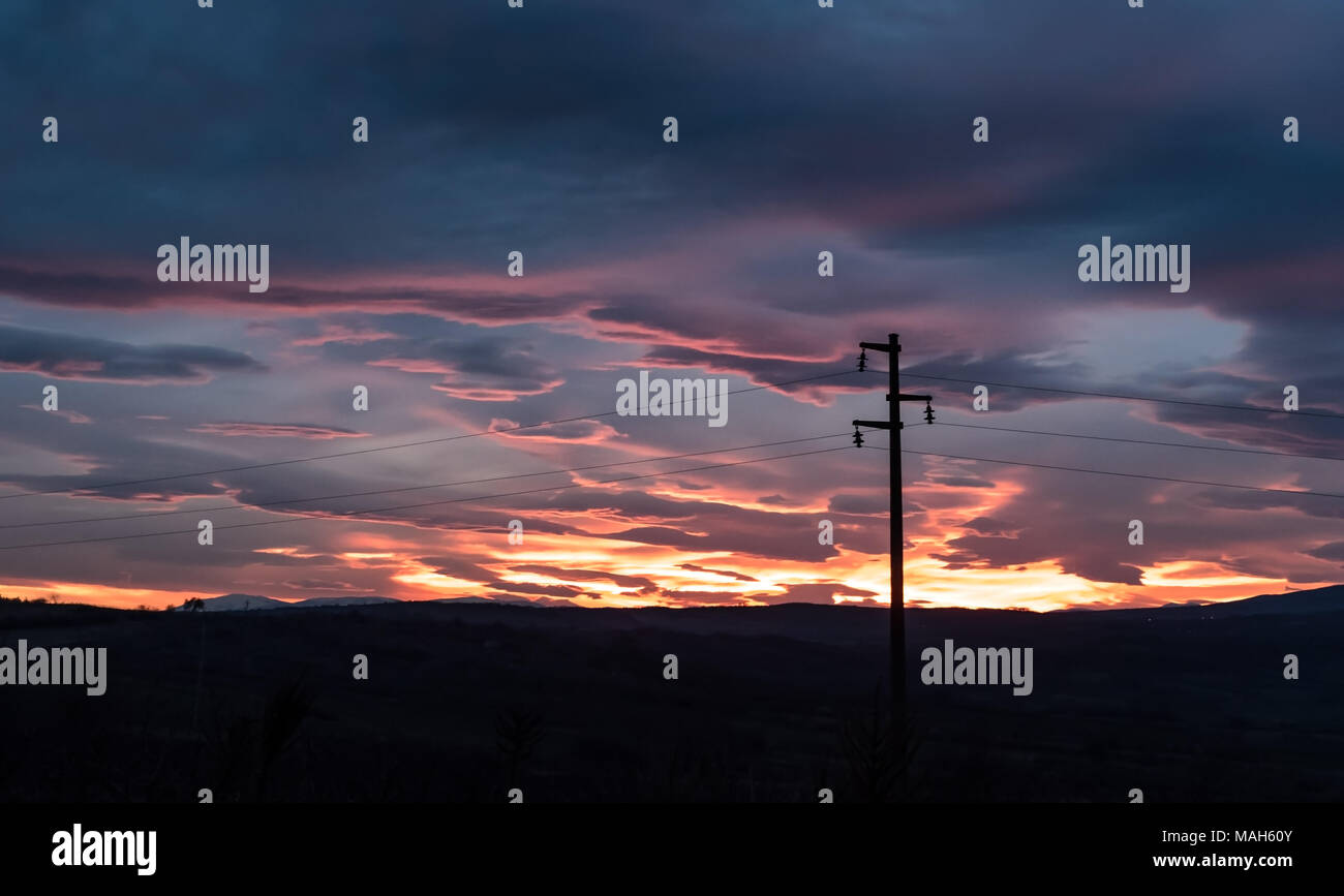 Power line - Single column in front of dramatic sky at sunset, near twilight Stock Photo