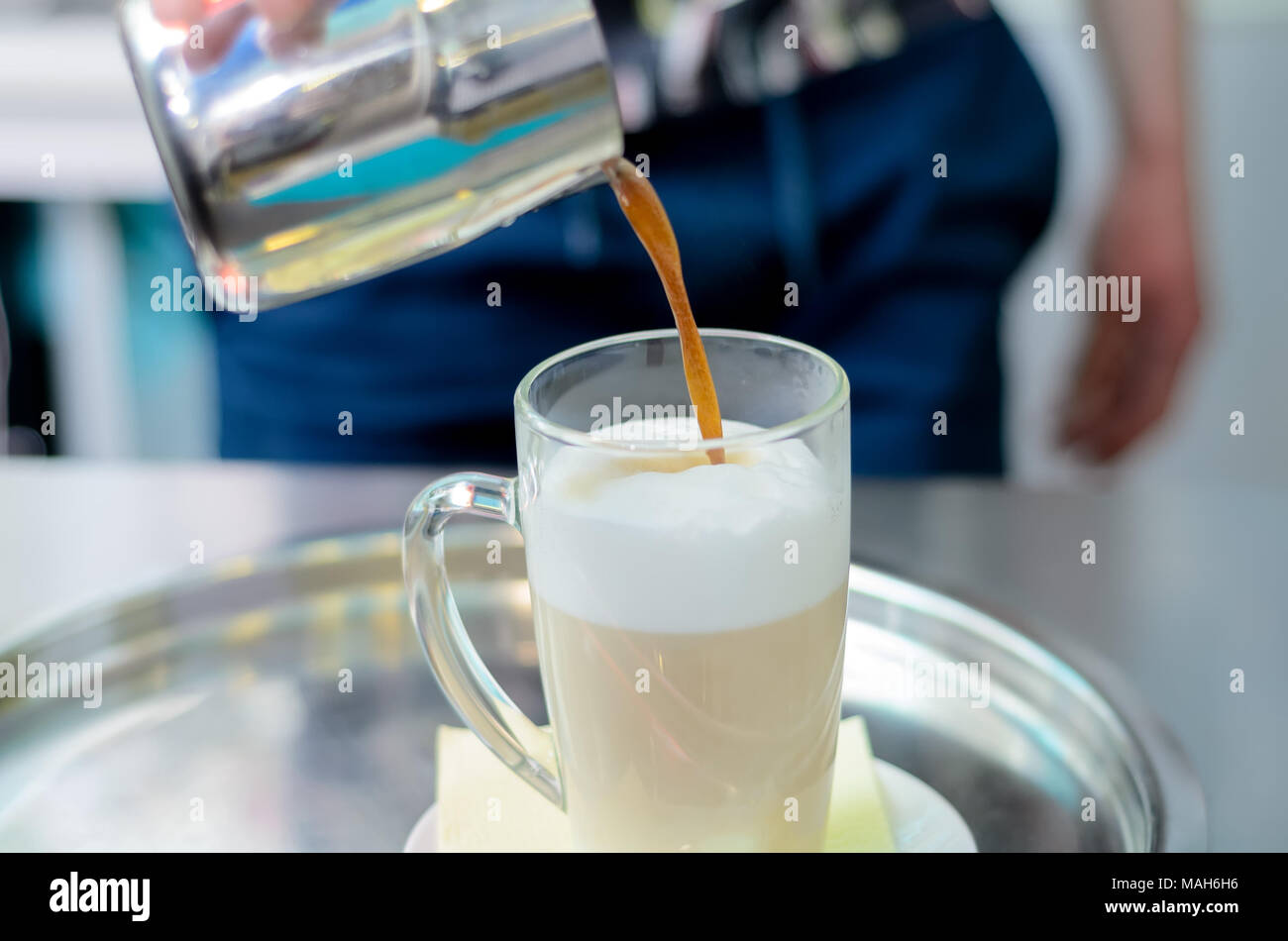 Man pours coffee latte in tall glass Stock Photo