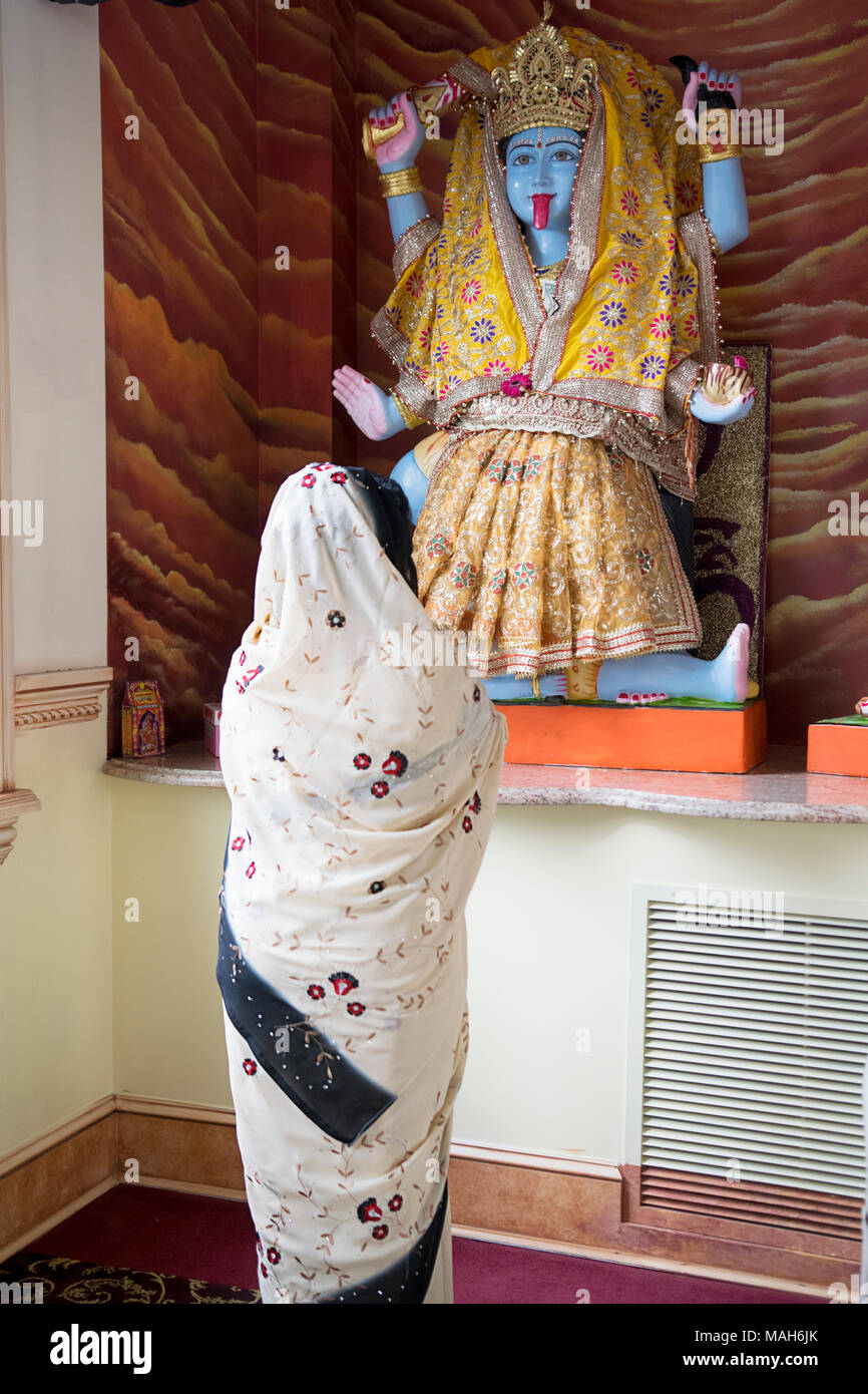 A Hindu worshiper praying & meditating in front of a statue of the