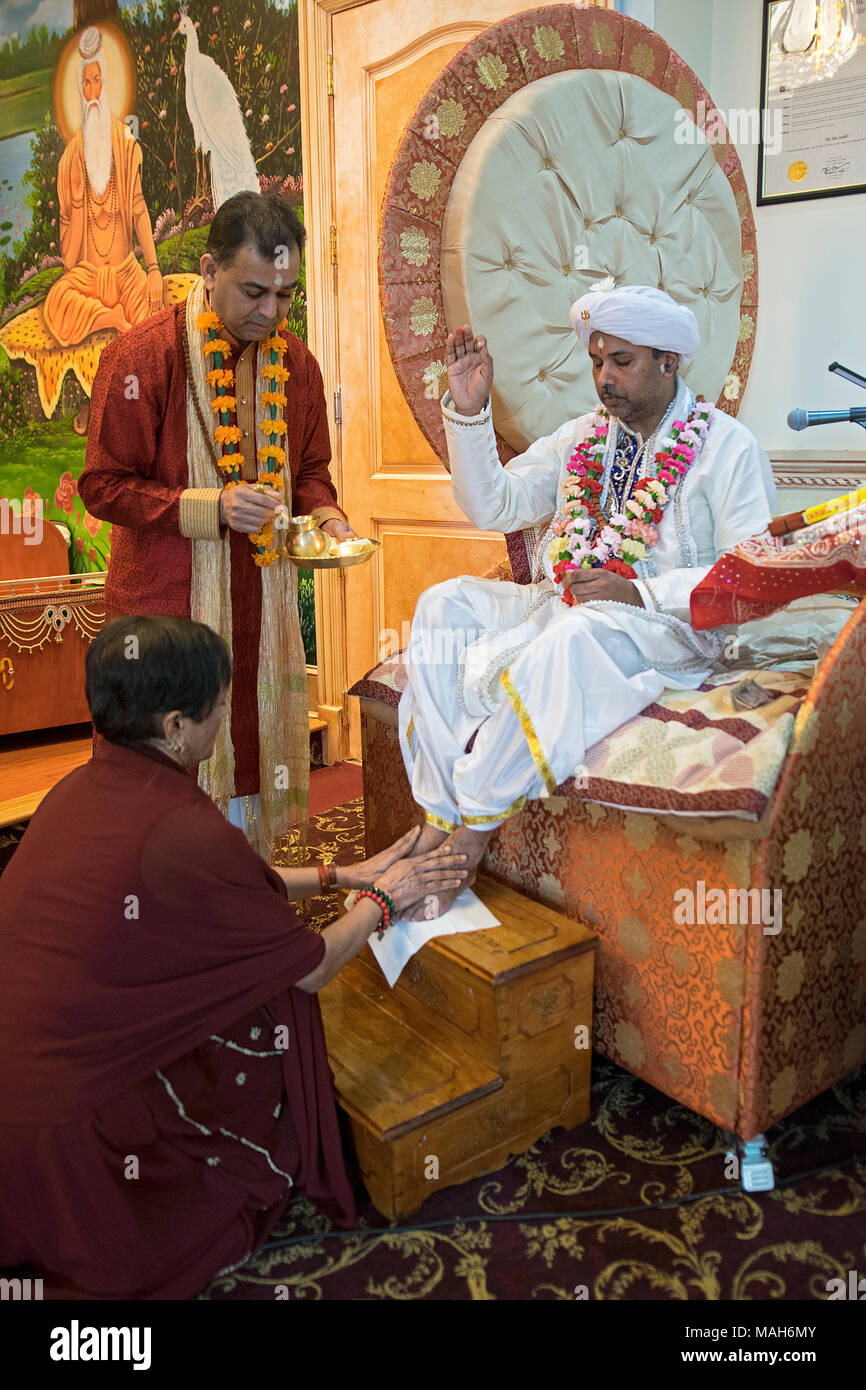 A female worshiper washes the feet of a priest at the Tulsi Mandir temple in South Richmond Hill, Queens, New York. Stock Photo