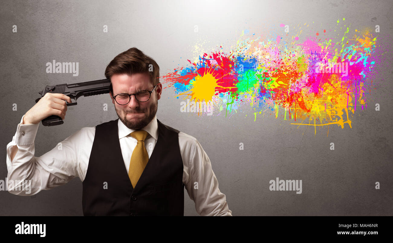 Man shoots his head with gun and colorful splotch are coming out from his head Stock Photo