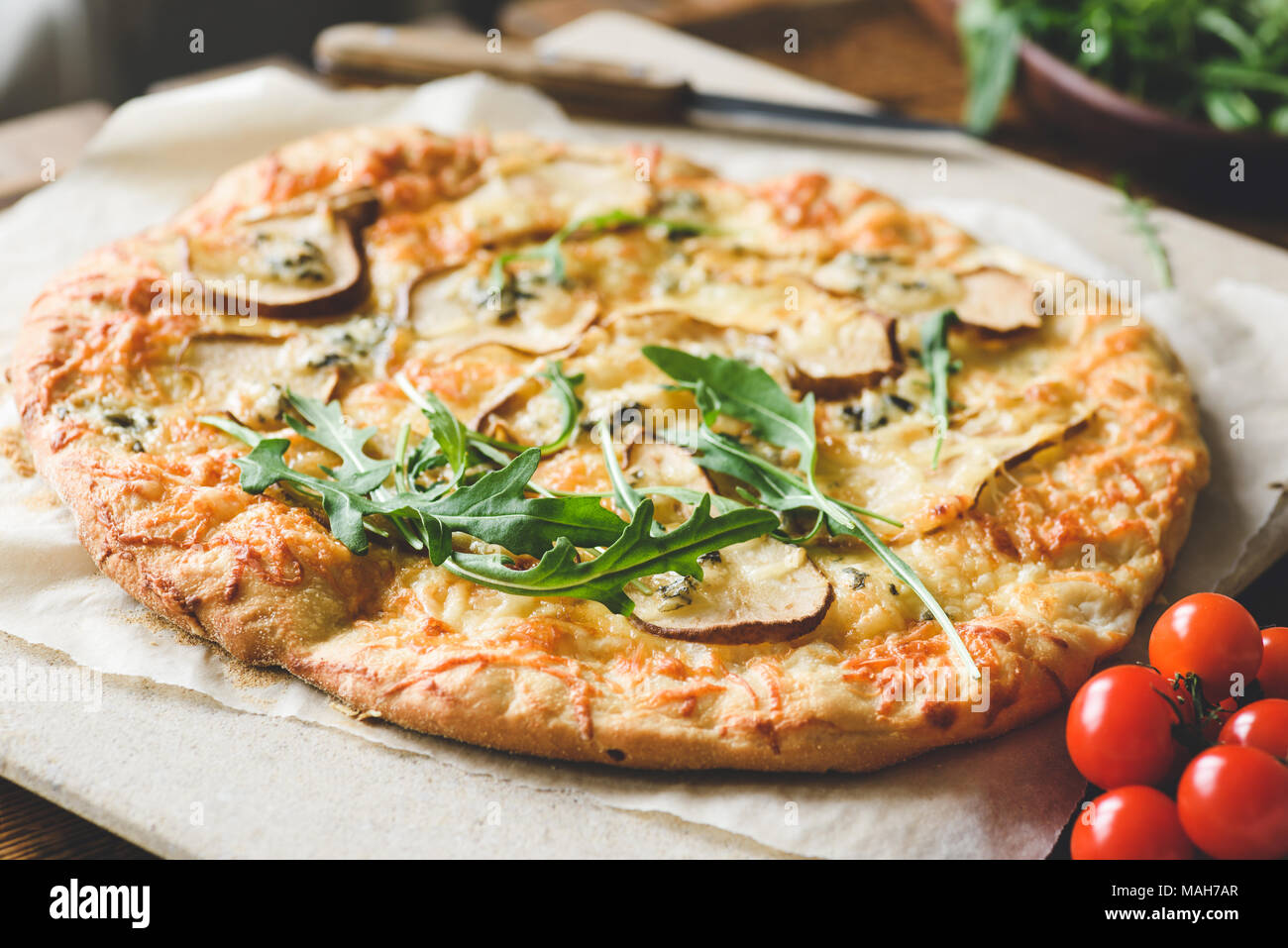 Homemade four cheese pizza with pear and fresh arugula, ruccola. Closeup view, selective focus Stock Photo