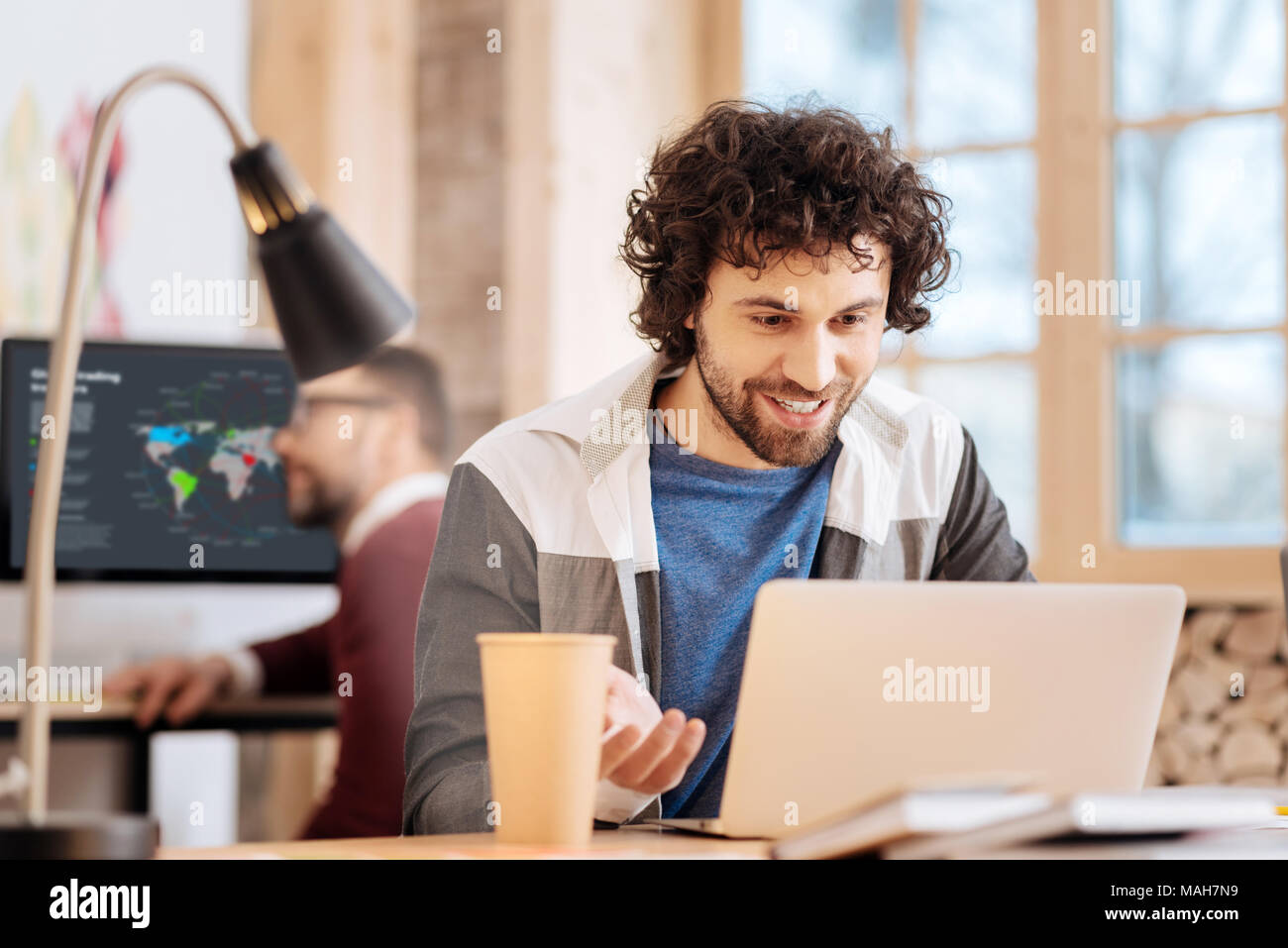 Delighted young man working on his laptop Stock Photo