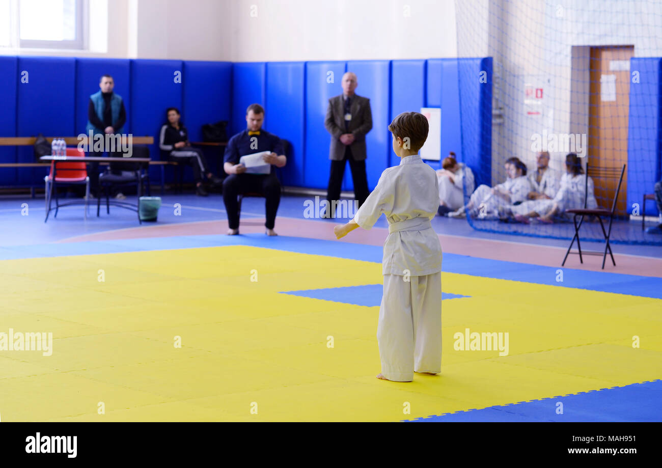 Competition among children in karate,kata.A 78 year old boy stands with his back on the tatami