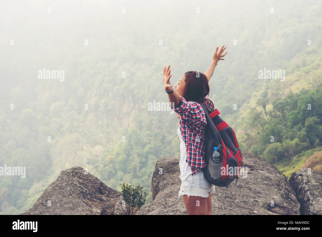 Hiker with backpack standing on top of a mountain with raised hands and ...