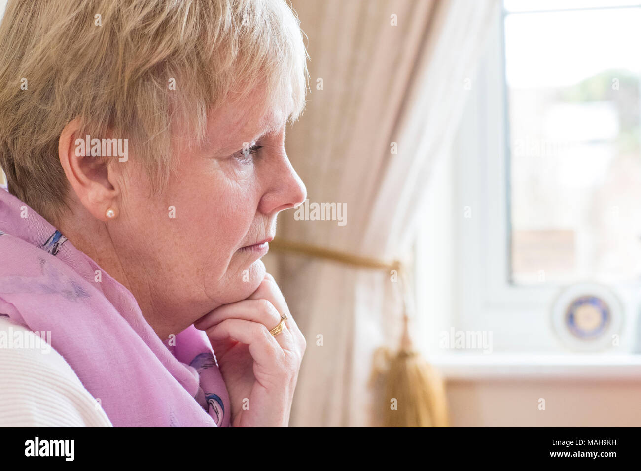 Side View Of Depressed Senior Woman At Home Stock Photo