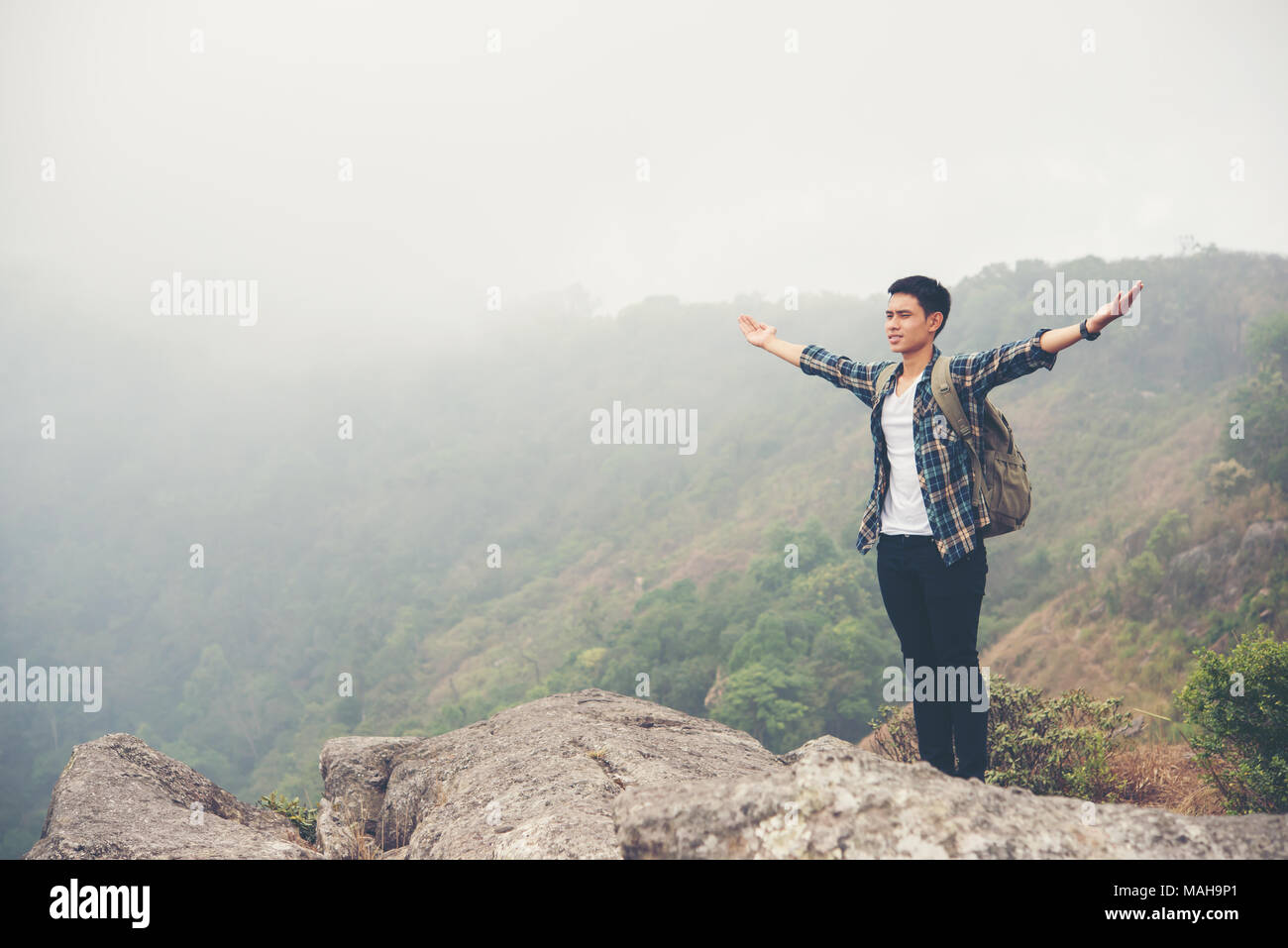 Hiker with backpack standing on top of a mountain with raised hands ...