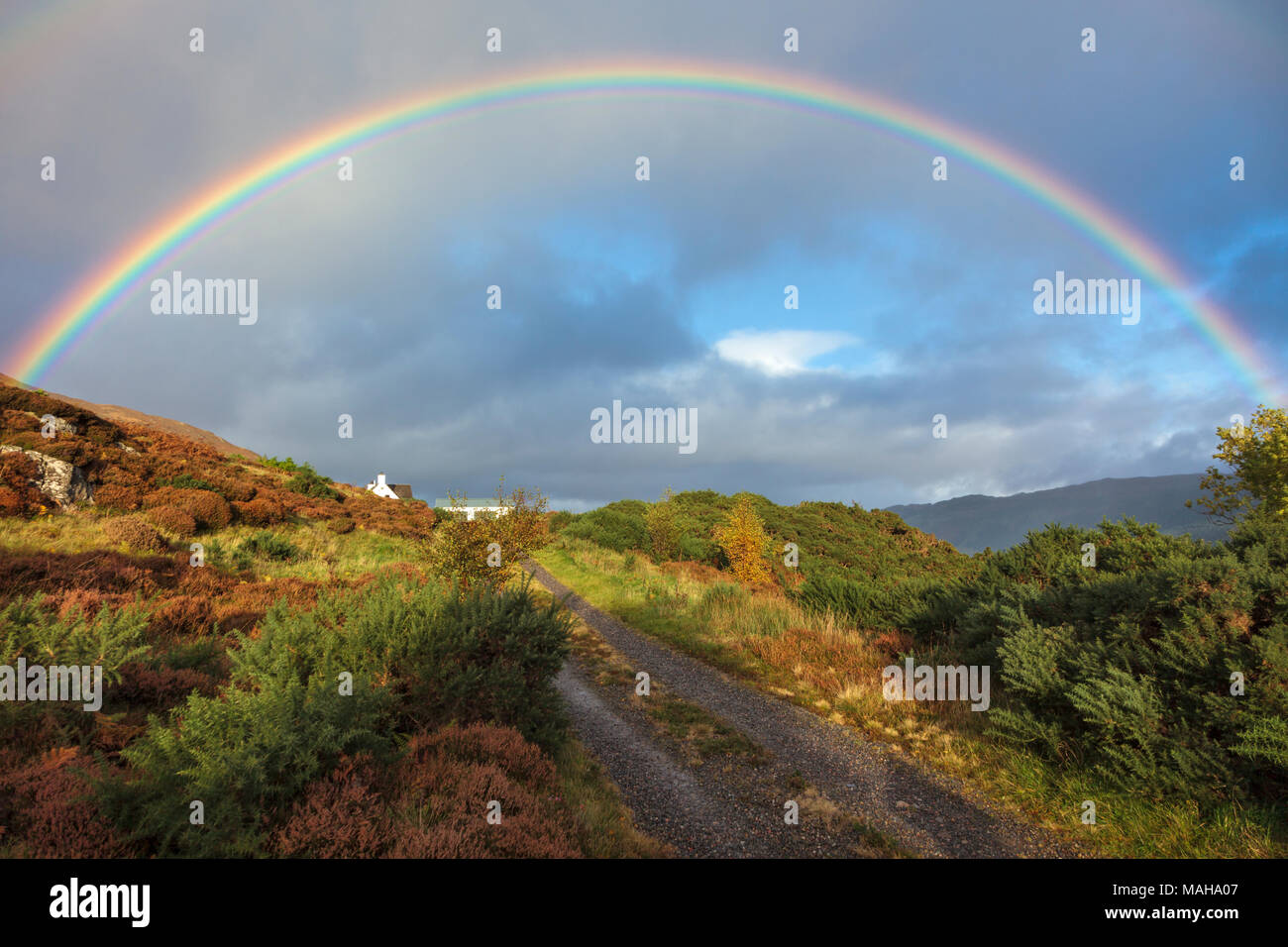 Rainbow over North Strome, Lochcarron, Wester Ross in the Scottish Highlands, Scotland UK, with a distant white cottage nestled into the hillside. Stock Photo