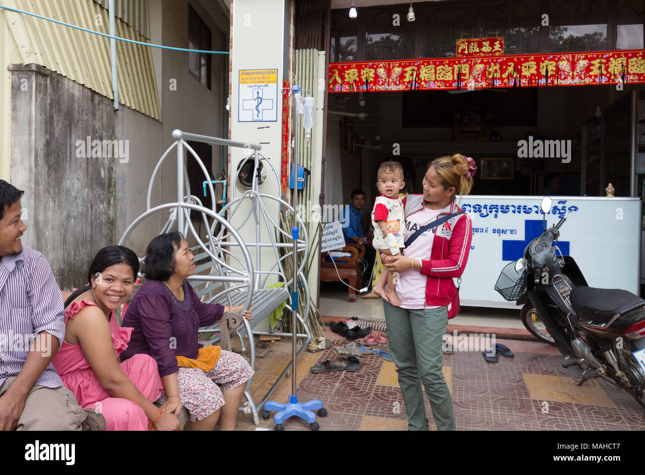 Cambodia healthcare - a woman with her baby who is attached to a drip outside a local health clinic, Kampong Thom, Cambodia, South East Asia Stock Photo