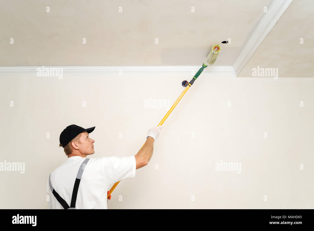 Painting walls and ceilings. Painter paints using roller Stock Photo