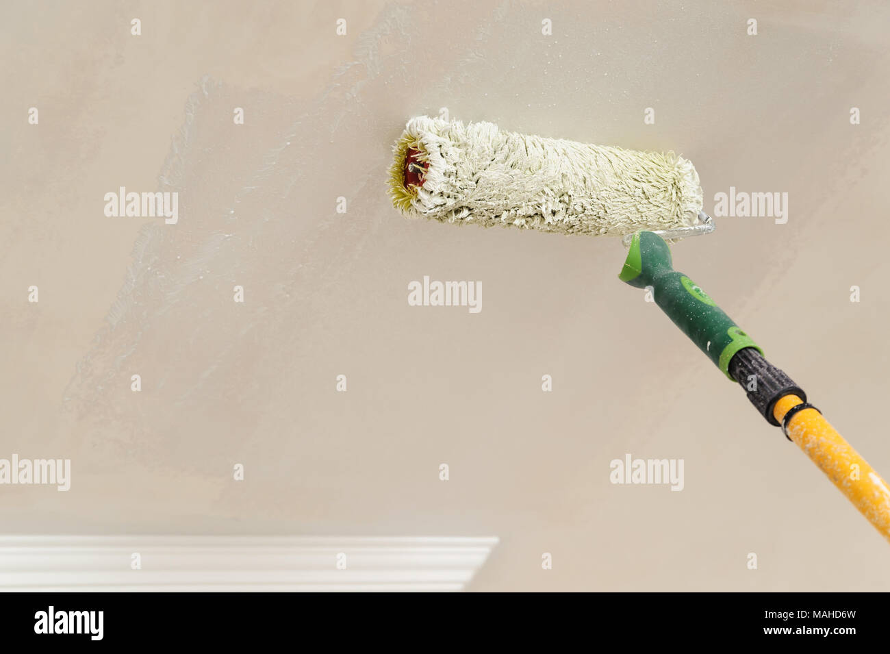 Painting walls and ceilings. Painter paints using roller Stock Photo