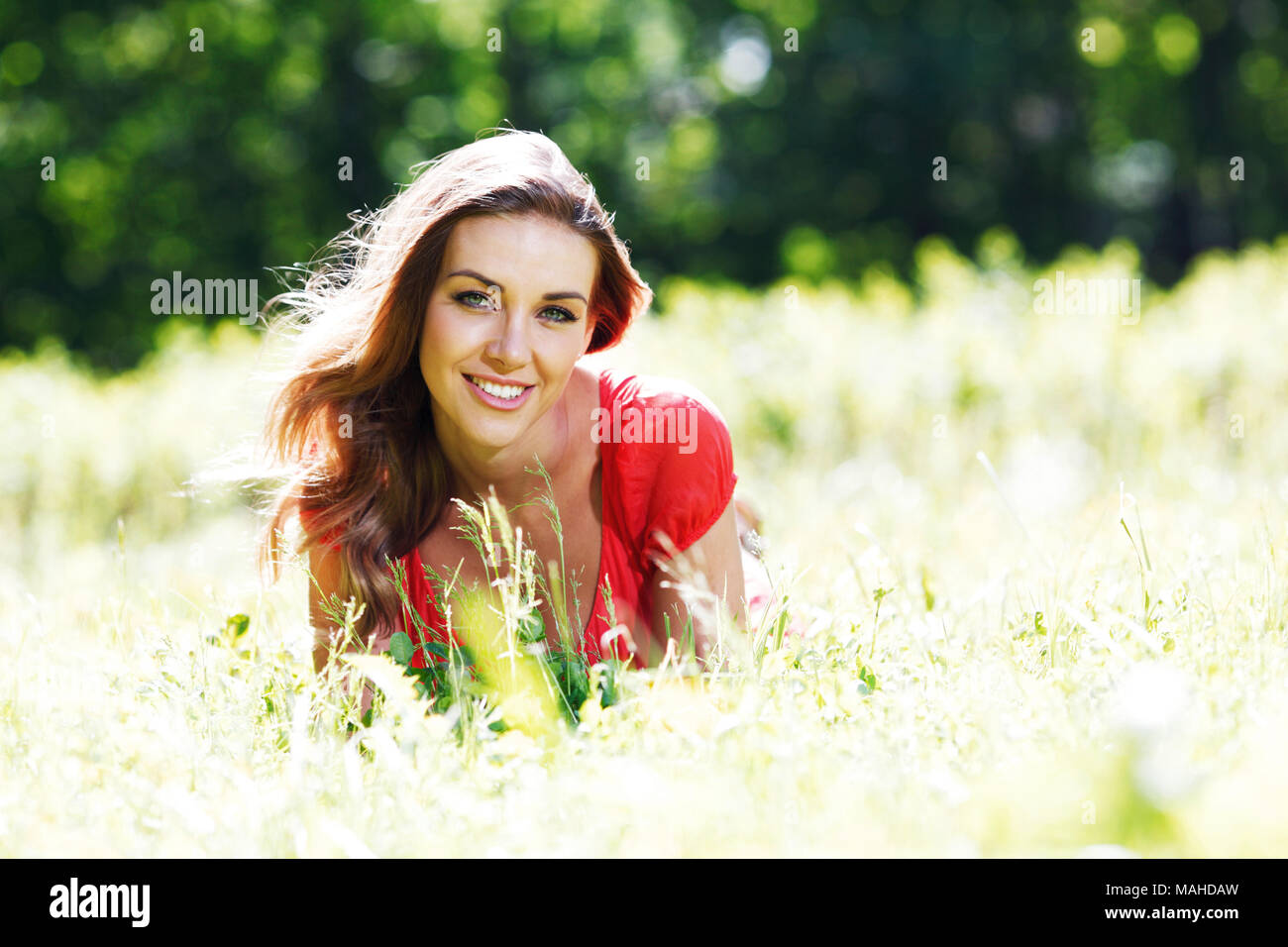 beautiful young woman in red dress lying on grass Stock Photo - Alamy