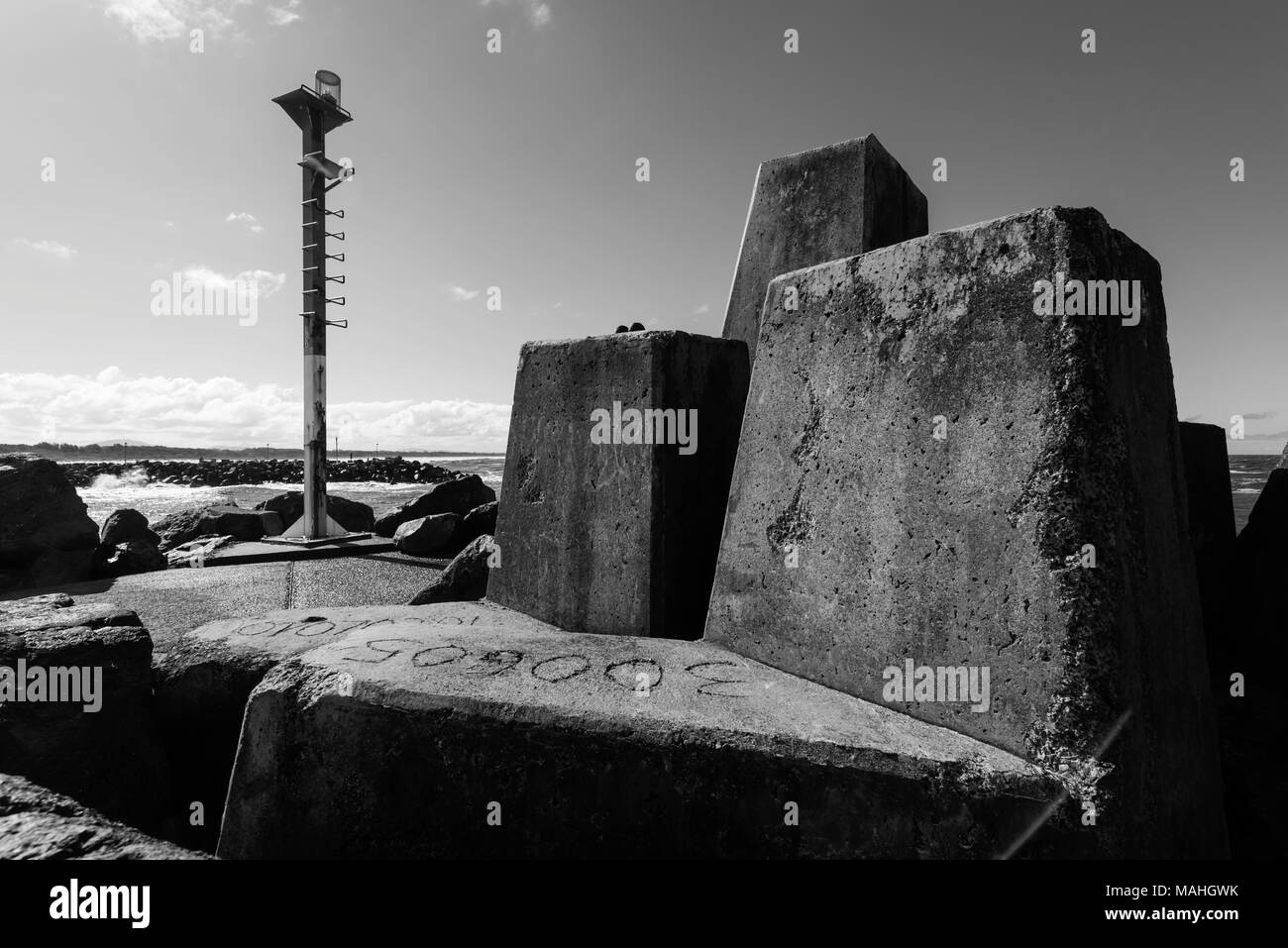 massive concrete tetrapod blocks and a beacon at the southern breakwater entrance to Wallis Lake at Forster Tuncurry, NSW, Australia Stock Photo