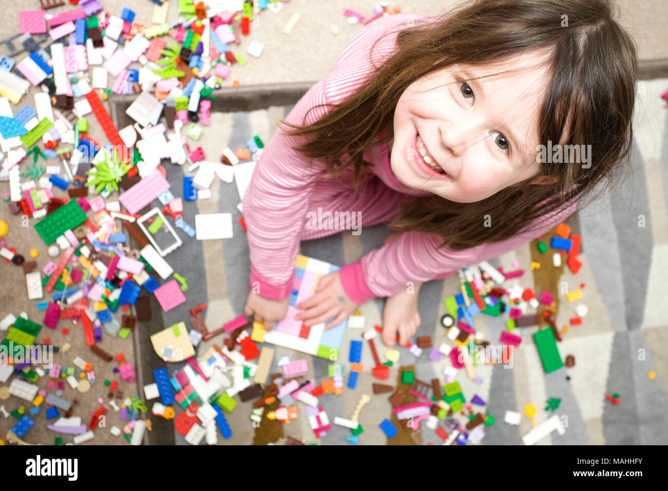 Young smiling girl looking at camera playing with lego Stock Photo