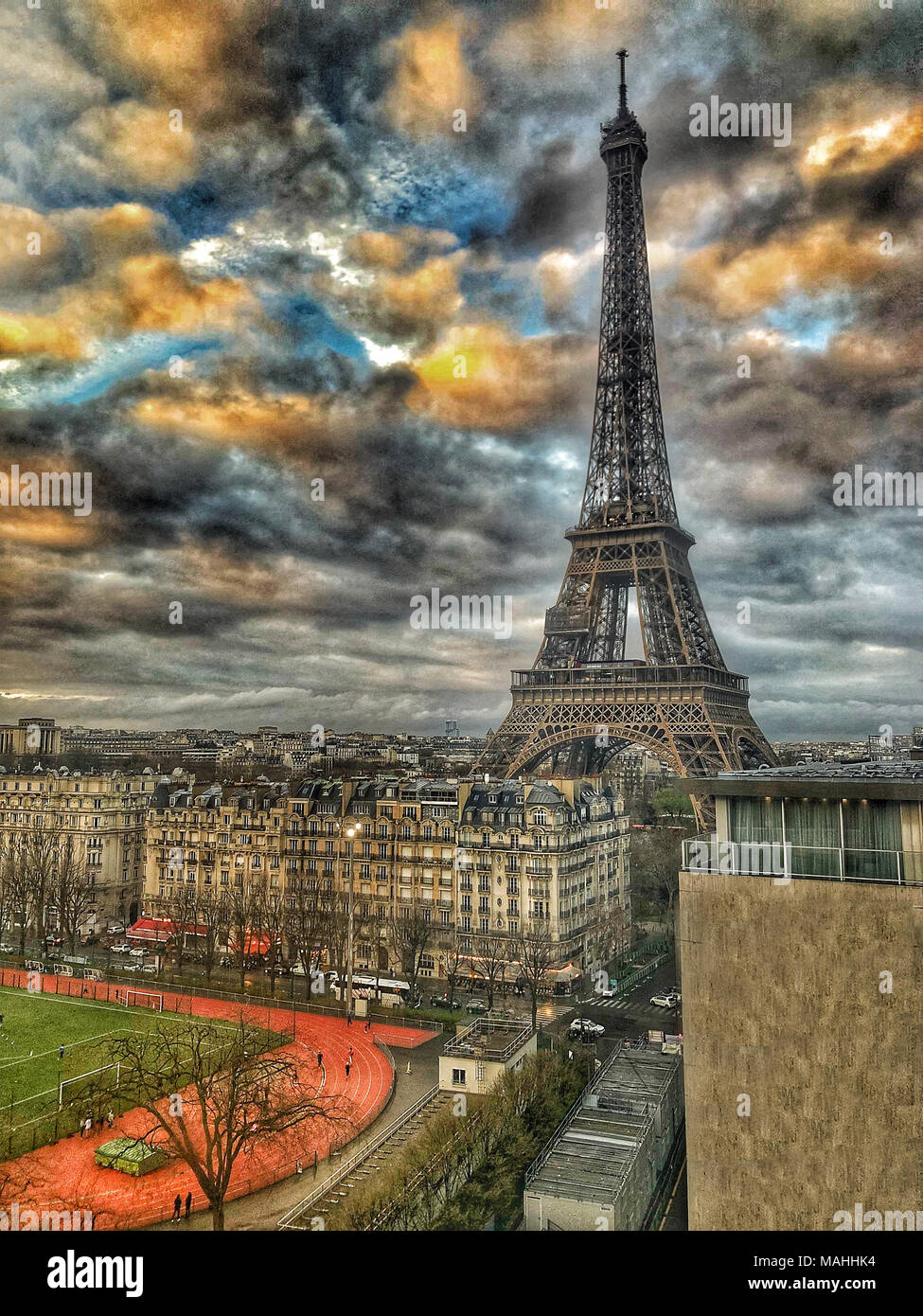 Eiffel Tower in Paris seen from a Building Behind During a Dramatic Sunset Stock Photo