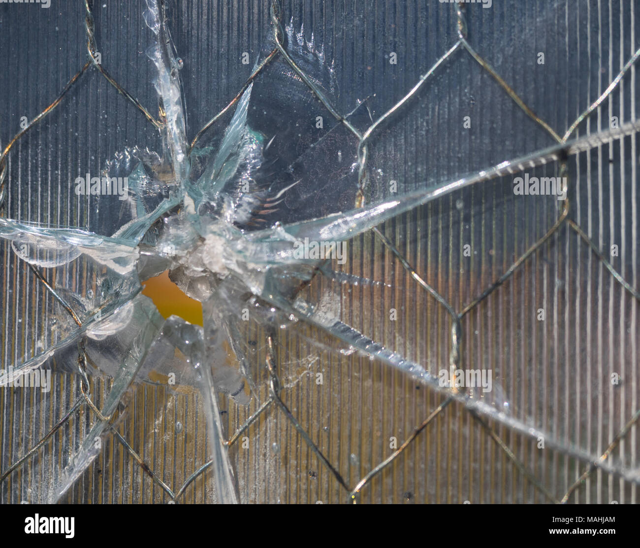 Bullet With Ridges Close up of a bullet hole through wire mesh glass. The glass has ridges ...