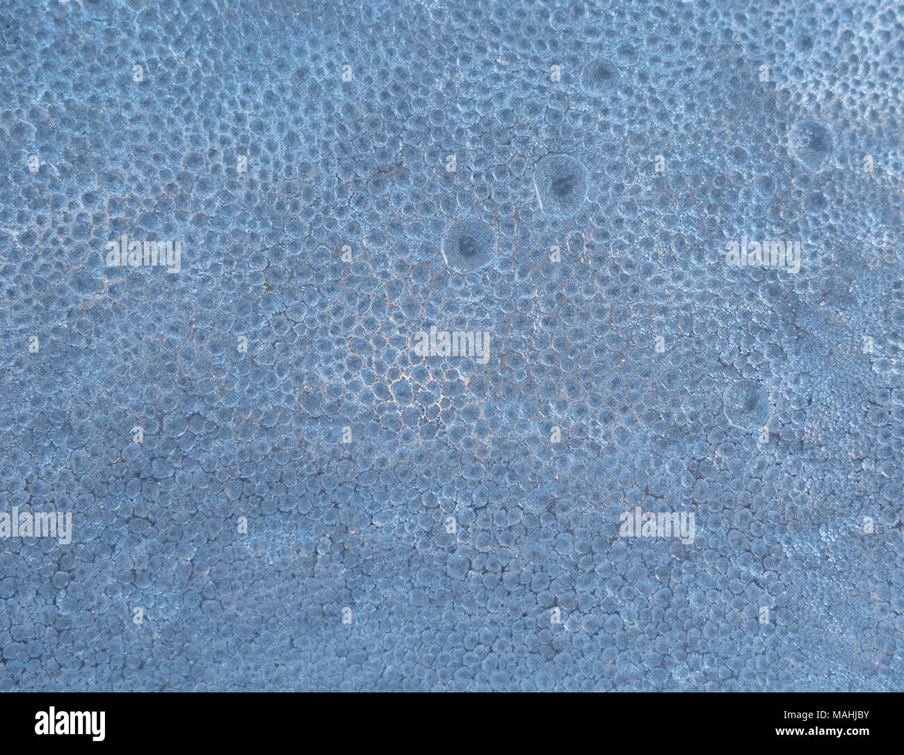 Close up of a frosty window with blue gray ice pebbles that are backlit. Stock Photo