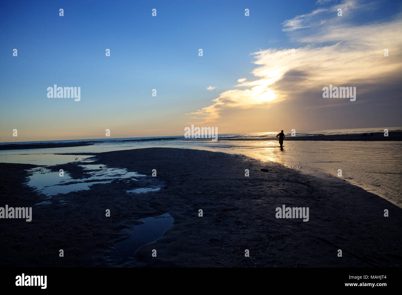 Man Silhouette at sunset in font of a River leading to the ocean at Clam Pass at dusk in Naples, Florida Stock Photo