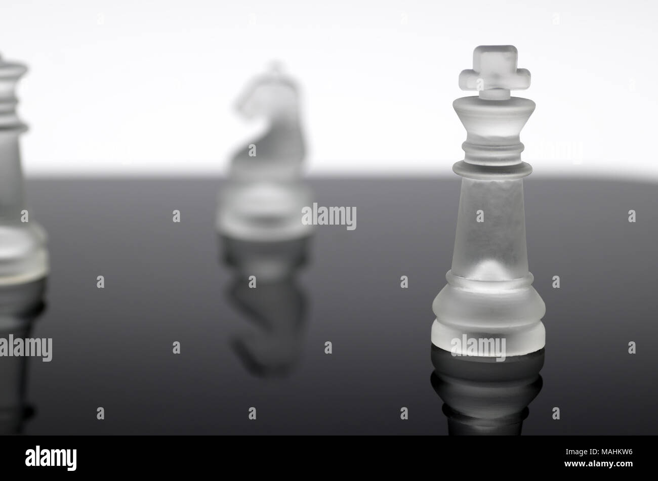 It is a chess piece, a translucent king that stands out among other pieces that are intentionally blurred out. Stock Photo